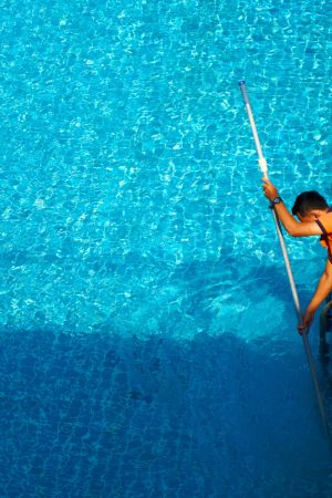 Top view of a worker cleaning a swimming pool in a private house in summer.